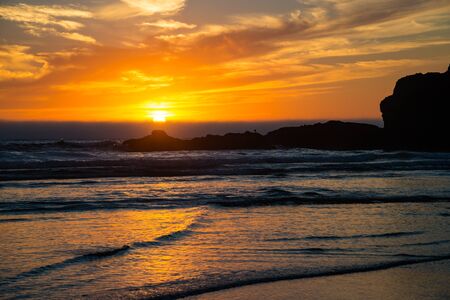 Orange sunset and waves on beach on Central Oregon coastの写真素材