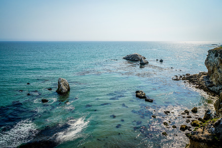 The awesome rocky cliffs of the California coast glistening in the afternoon sunshine.の写真素材
