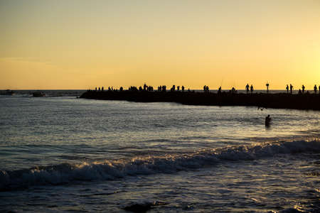 A warm orange sunset at the Jetty in Venice with dark silhouettes cast against the setting sun.の写真素材