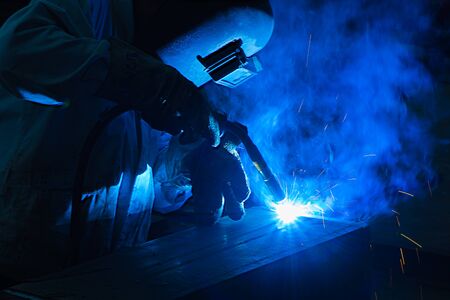 Welder is welding metal with argon-arc in workshop at night.の写真素材