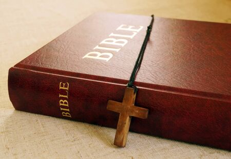 Red Bible book and wooden cross on desktop