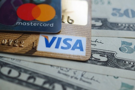 Khmelnitskyi, Ukraine - May 5, 2019: VISA and Mastercard credit card with american dollars. Finance concept.のeditorial素材