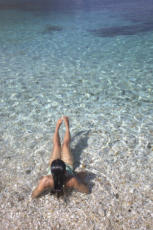 Girl in bright water with white pebblesの写真素材