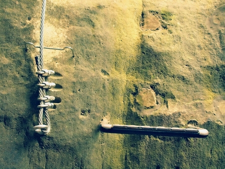Climbers way. Iron twisted rope fixed in the block by screws snap hooks. The rope end anchored into sandstone rock.の写真素材