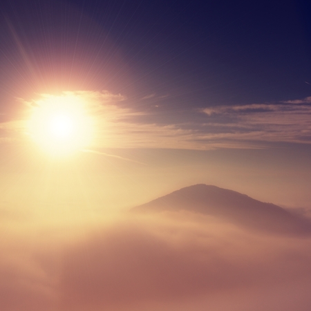 Magnificent heavy mist in landscape. Autumn fogy sunrise in a countryside. Hill increased from fog, the fog is colored to golden and orange.の写真素材