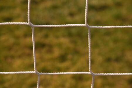 Detail of crossed soccer nets, football in soccer goal net with natural grass on football playground...