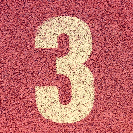White track number on red rubber racetrack, texture of running racetracks in small stadiumの写真素材
