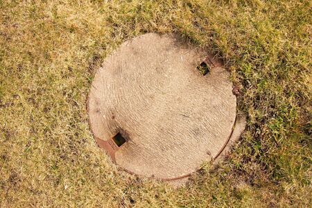 Concrete manhole cover drainage system in the midst of cropped grassの写真素材
