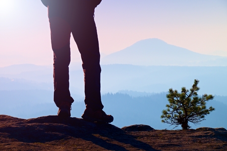 Man hiker legs in tourist boots stand on mountain rocky peakの写真素材