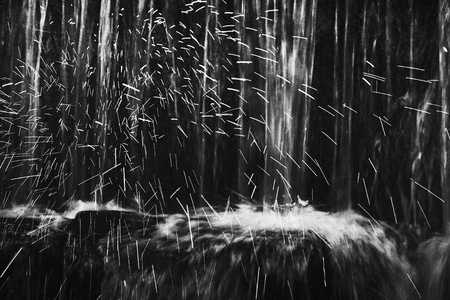 Shinning drops. Cascade of small weir on mountain stream, big mossy boulders.の写真素材