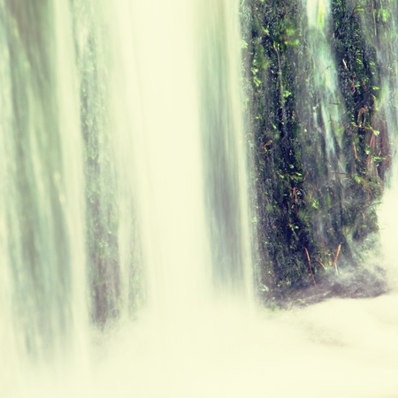 Small waterfall on small mountain stream, mossy sandstone block. Clear water is hurry jumping down into small pool.の写真素材