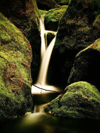 Weir in mountain stream. Colorful leaves  on stones into water. Mossy boulders.の写真素材