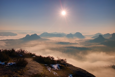 Dreamy misty landscape. Majestic mountain cut the lighting mist. Deep valley is full of colorful fog and rocky hills are sticking up to Sun.の写真素材