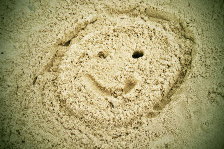 Drawn smiley face in summer beach sand.の写真素材