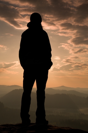 Sad girl stand on the sharp corner of sandstone rock and watch over valley's Sun.の写真素材