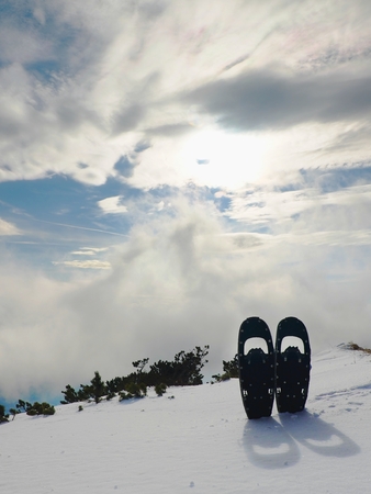 Snowshoes in snow at mountain peak, nice sunny winter dayの写真素材