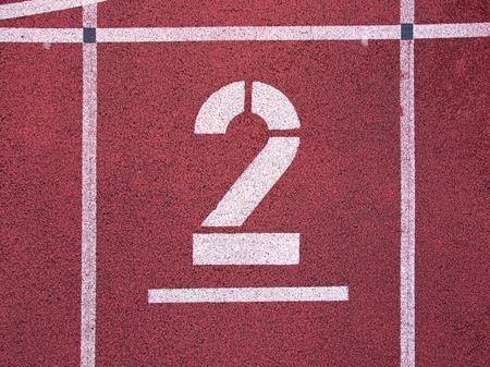 Number two. Big white track number on red rubber racetrack. Gentle textured running racetracks in small outdoor stadium.の写真素材
