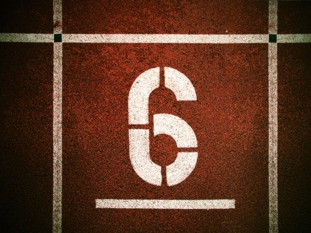 Number six. White athletic track number on red rubber racetrack, texture of running racetracks in...