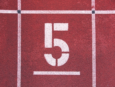 Number five. Big white track number on red rubber racetrack. Gentle textured running racetracks in...