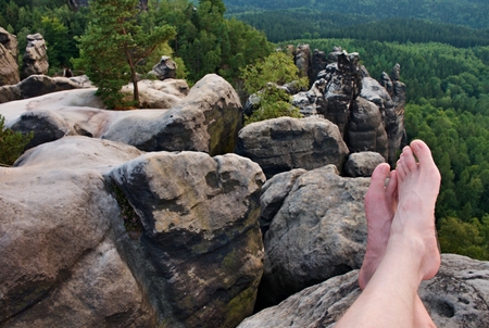 Naked male sweaty legs on peak of rock above valley.の写真素材