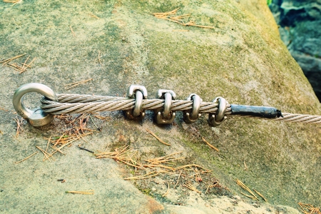Mountain wall with carabine in the rock. End of the iron rope in loop.