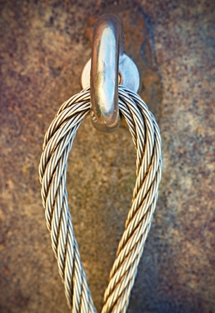 Detail of steel bolt anchor eye in sandstone rock. The end knot  of steel rope. Climbers path via ferrata. Iron twisted rope fixed in block.の写真素材