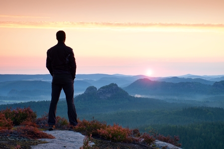 Hiker in sportswear stand on the peak of sandstone rock in rock empires park and watching over the misty and foggy morning valley to Sun. Beautiful moment the miracle of natureの写真素材