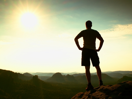 Happy hiker is standing on the peak of sandstone rock in rock empires park and watching over the misty and foggy morning valley to Sun.の写真素材