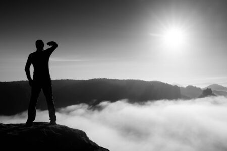 Funny boy on the sharp peak of rock in rock empires park is watching over the misty and foggy morning valley to Sunの写真素材