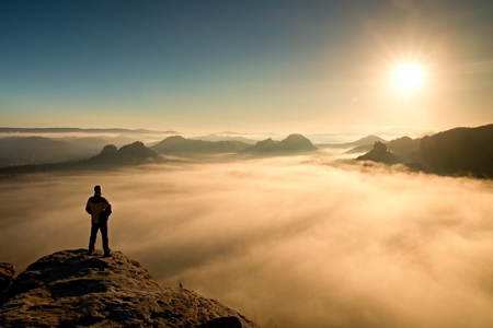 Man stands on the peak of sandstone rock in national park Saxony Switzerland and watching to Sun. Beautiful moment the miracle of natureの写真素材