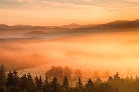Pink daybreak in hilly landcape. Autumn misty morning in a beautiful hills. Peaks of hills are sticking out from fogの写真素材