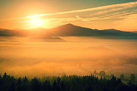 Gentle misty landscape in hilly country. Retro style filter. Orange toning effect.の写真素材