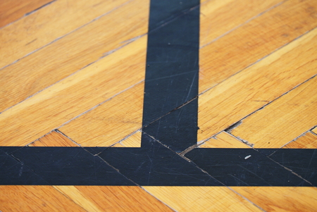 Worn out wooden floor of sports hall with colorful marking lines.の写真素材
