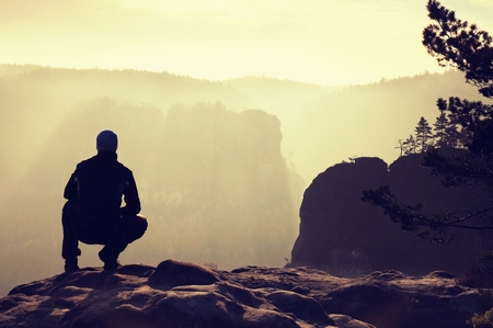 Hiker stand at heather bush on the corner of empire bellow pine tree. Man is watching over the misty and foggy morning's Sun Valleyの写真素材