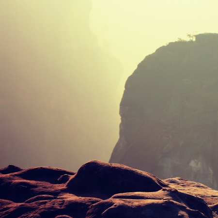 Dreamy sunrise on the top of the rocky mountain with view into the misty valleyの写真素材