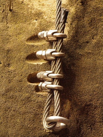 Climbers way. Iron twisted rope fixed in block by screws snap hooks. The rope end anchored into sandstone rock.の写真素材