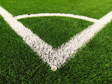 Football playground corner on artificial green turf ground with painted white line marks. Milled black rubber in basic.の写真素材