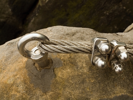 Chrome steel anchor eye concreted in rock and the steel rope end. Climbers path in rocks via...