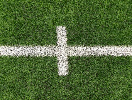 Detail of crossed white lines on football playground. Detail of lines in a soccer field. Plastic grass and finely ground black rubber.の写真素材