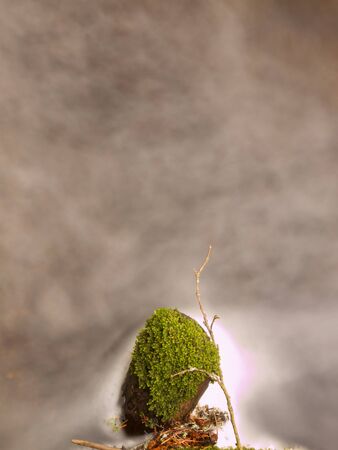 Mossy stone in blurred colorful waves of mountain stream. Cold water is running and turning Between boulders and bubbles create trails on the level. Colorful bubbles on stones and into water.の写真素材