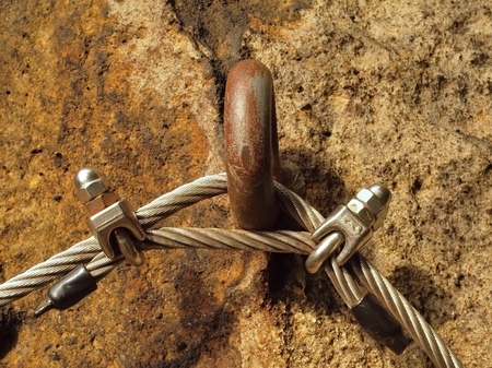 Detail of rope end anchored into sandstone rock. Iron twisted rope fixed in the block by screws snap hooks.の写真素材