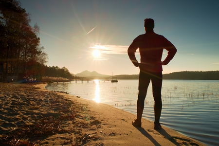 Silhouette of man on decline seeing over bay to sunの写真素材