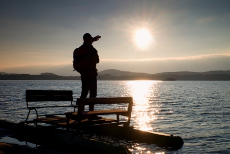 Hiker silhouette with backpack on abandoned  pedal boat in the sunset. Autumn sunny day  at seaの写真素材