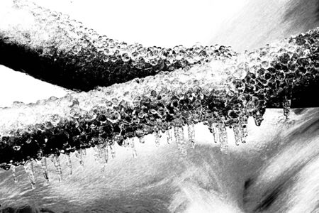 Black and white dashed retro sketch. Freeze winter view to icicles on twigs and icy boulders above...