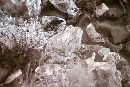 Beautiful big piece of ice with abstract cracks inside. Fallen icicle bellow waterfall, stony and...