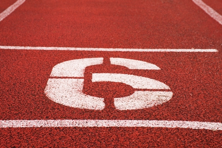 Number six. White athletic track number on red rubber racetrack, texture of racetracks in small stadiumの写真素材
