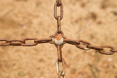 Joined old rusty chain in cross, close up view of poor chain and screwの写真素材