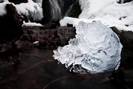 Spiky piece of icrystal ce with abstract cracks inside. Fallen icicle bellow waterfall, stony and...