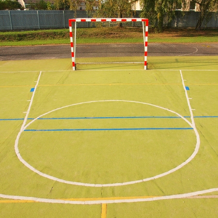 Outdoor handball playground. Dry plastic light green surface on ground blue and white lines ..の写真素材
