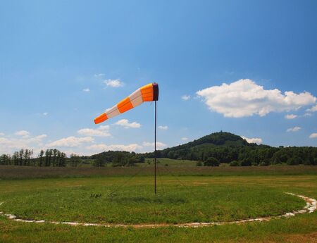 Summer hot day on the sport airport with abandoned windsock, wind is blowing and windsock is movingの写真素材